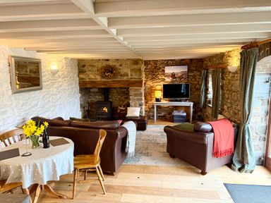 A living room with a sofa, dining table, and television at Stable Cottage in Newport, Pembrokeshire