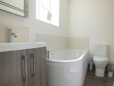 A bathroom with a bathtub a toilet and a sink with a cabinet at Derlwyn in Newport Pembrokeshire