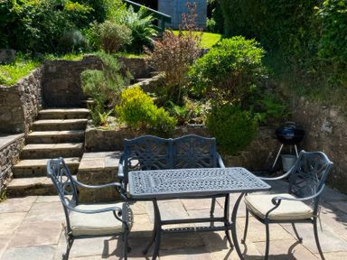 A garden with a table and chairs and steps at Derlwyn Newport, Pembrokeshire