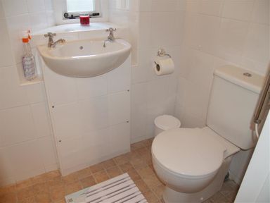 A bathroom with a toilet sink toilet paper and cleaning spray at West End Cottage in Newport Pembrokeshire