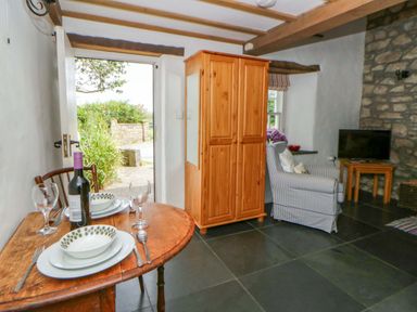 A living room with a dining table and wardrobe at West End Cottage in Newport, Pembrokeshire