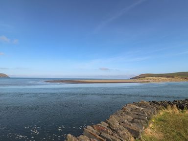 A beach with water and rocks at West End Cottage Newport, Pembrokeshire