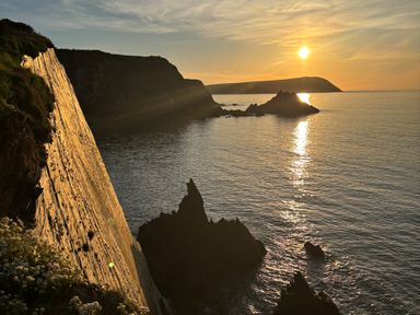 A view of cliffs and ocean with the sun setting at West End Cottage in Newport, Pembrokeshire