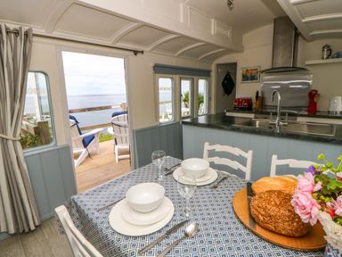 A kitchen with a dining table and chairs at Clifftop Carriage in Aberporth, Ceredigion