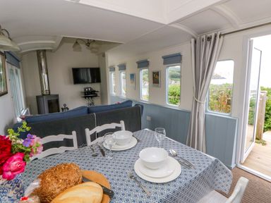 A dining room with a table set for meals at Clifftop Carriage Aberporth, Ceredigion