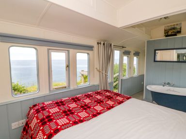A bedroom with a bed and bathtub at Clifftop Carriage, Aberporth, Ceredigion