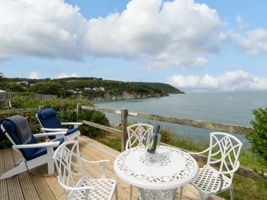 A patio area with chairs and table overlooking the ocean at Clifftop Carriage in Aberporth, Ceredigion