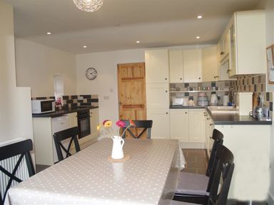 A kitchen with a dining table covered with a polka dot tablecloth and a vase with flowers at Gellifor in St Dogmaels Pembrokeshire