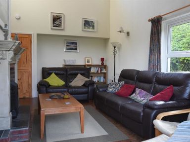A living room with two leather sofas a wooden coffee table and bookshelf at Gellifor in St Dogmaels Pembrokeshire