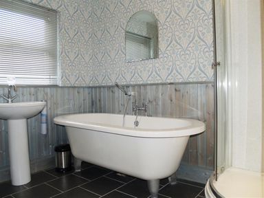 A bathroom with a freestanding bathtub a pedestal sink a shower enclosure and a mirror at Gellifor in St Dogmaels Pembrokeshire