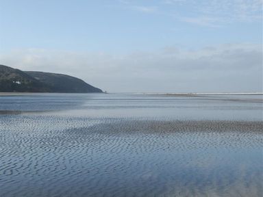 A wide shallow tidal area with rippled water and a distant hill under a partly cloudy sky at Gellifor in St Dogmaels Pembrokeshire