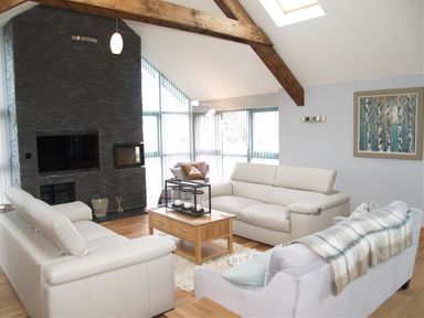A living room with sofas and a wooden coffee table near a stone fireplace at Seabrook Broad Haven Pembrokeshire