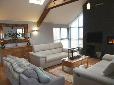 A living room with sofas a wooden coffee table and fireplace at Seabrook in Broad Haven Pembrokeshire