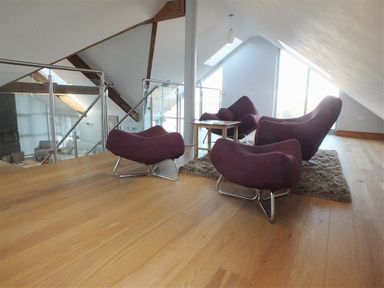 A seating area with four purple chairs on a rug around a wooden table in an attic space with wooden floor and glass railing at Seabrook in Broad Haven Pembrokeshire