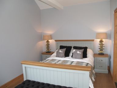 A bedroom with a double bed two bedside tables with lamps and cushions on the bed at Seabrook Broad Haven Pembrokeshire