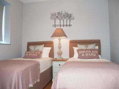 A bedroom with two single beds two pillows a lamp and wall decoration at Seabrook Broad Haven Pembrokeshire