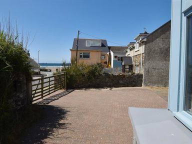 A paved driveway with a wooden gate and houses with a view of the sea at Seabrook in Broad Haven Pembrokeshire