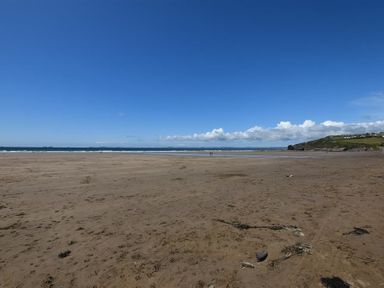 A wide sandy beach with sea in the distance and a green hill on the right at Seabrook Broad Haven Pembrokeshire