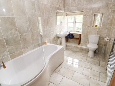 A bathroom with a bathtub sink toilet and window at Gwyddno Lodge in Narberth Pembrokeshire