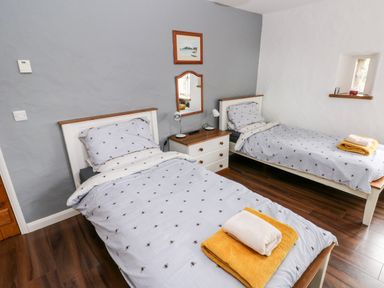 A bedroom with two single beds bedside table and a small window at Gwyddno Lodge in Narberth Pembrokeshire