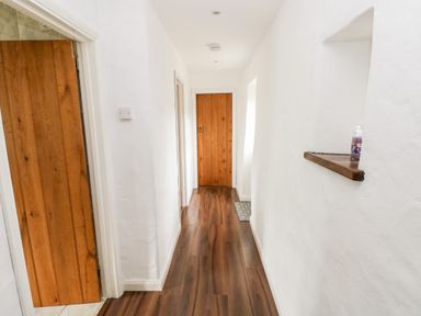 A hallway with wooden doors white walls and wood flooring at Gwyddno Lodge in Narberth Pembrokeshire