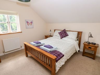 A bedroom with a wooden bed and two bedside tables with lamps at Gwyddno Lodge in Narberth Pembrokeshire