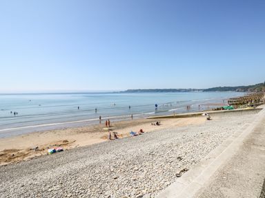 A beach with people on the sand and in the water and a pebble embankment with steps at Gwyddno Lodge in Narberth Pembrokeshire