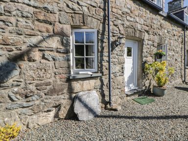 A stone wall with a window and door at End Cottage in Newport, Pembrokeshire