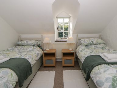 A bedroom with two beds and a window at End Cottage Newport, Pembrokeshire