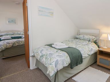 A bedroom with two beds and a bedside table at End Cottage Newport, Pembrokeshire