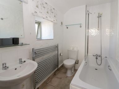 A bathroom with a bathtub, sink, toilet, and towel radiator at End Cottage Newport, Pembrokeshire