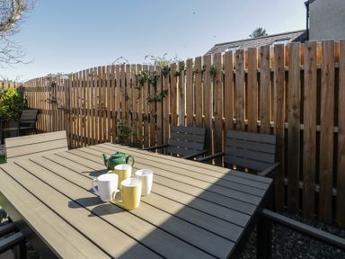A garden with a table and chairs and mugs at End Cottage, Newport, Pembrokeshire