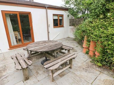 A garden with a wooden table and benches at Brynawelon in Newport, Pembrokeshire