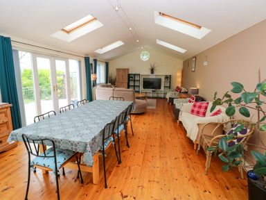 A living room with a dining table and a sofa at Greenbanks in Dinas Cross, Pembrokeshire