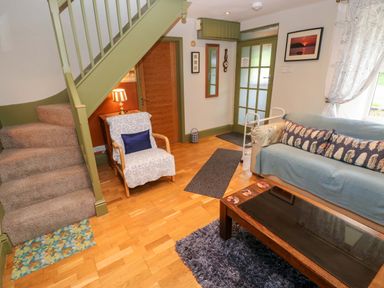 A living room with a couch and a staircase at Greenbanks in Dinas Cross, Pembrokeshire