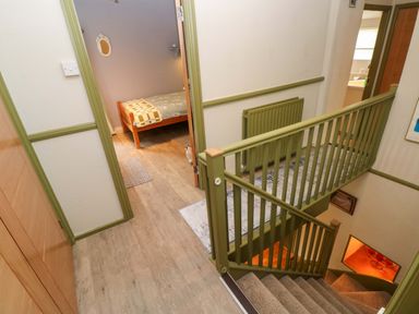 A hallway with a staircase and a door to a bedroom at Greenbanks in Dinas Cross, Pembrokeshire