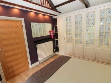 A bedroom with a wardrobe, mirror, and radiator at Greenbanks, Dinas Cross, Pembrokeshire