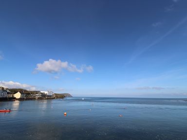 A coastal scene with houses on the left and calm sea with buoys and a kayak at Middle Cottage in Newport Pembrokeshire