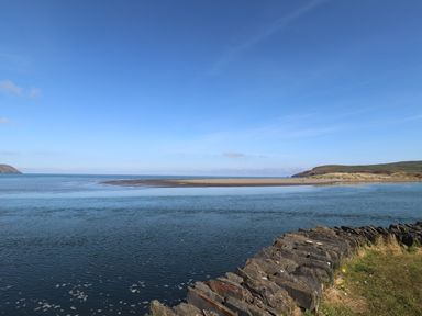 A coastal view with a rocky shoreline grassy edge and a sandbar in the sea at Middle Cottage in Newport Pembrokeshire