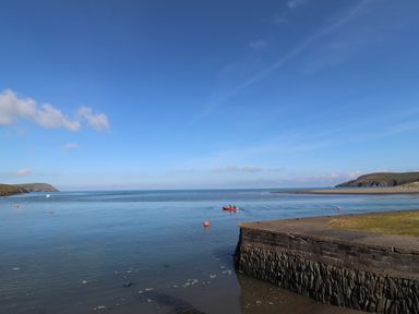 A body of water with a small red boat and buoys near a concrete structure at Middle Cottage in Newport Pembrokeshire