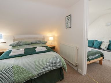 A bedroom with a bed and a seating area at Middle Cottage Newport, Pembrokeshire