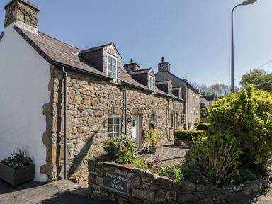 An exterior view of a stone house with garden at Pendre House and Cottages in Newport, Pembrokeshire