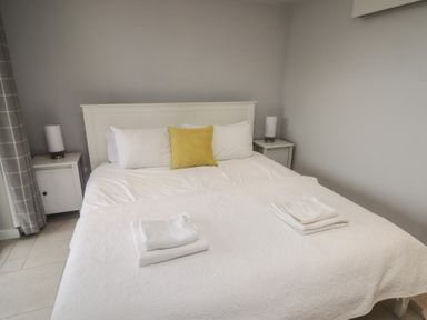 A bedroom with a white bed and yellow pillow and bedside tables with lamps at The Willows in Newport Pembrokeshire