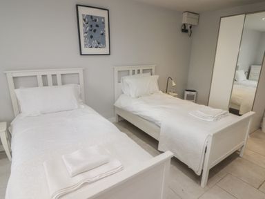 A bedroom with two single beds a bedside table and a wardrobe with mirrored doors at The Willows in Newport Pembrokeshire