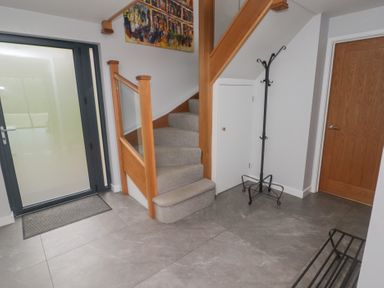 An entryway with a staircase a coat rack a door and a glass panel door at The Willows in Newport Pembrokeshire