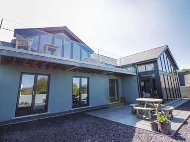 A house with a deck and outdoor table at The Willows in Newport, Pembrokeshire