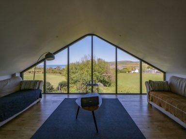 A living room with large windows showing the view at The Willows in Newport, Pembrokeshire
