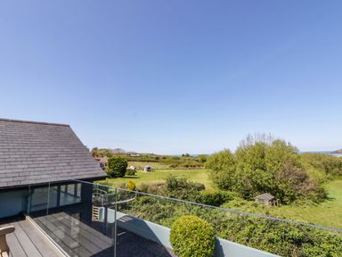 An outdoor balcony view overlooking trees and the sea at The Willows Newport, Pembrokeshire