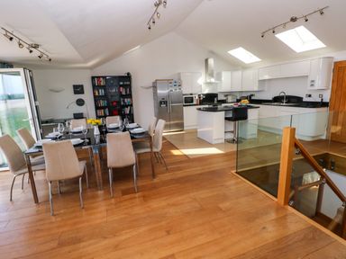 An open plan kitchen and dining area with a dining table and chairs kitchen appliances and island at Gwelfor Marloes in Marloes Pembrokeshire
