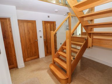 A hallway with three wooden doors and a wooden staircase with glass panels at Gwelfor  Marloes in Marloes Pembrokeshire